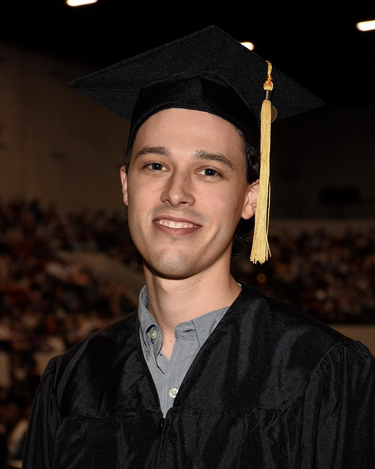 Stephen Chase Robinson smiling, wearing a black graduation cap and gown